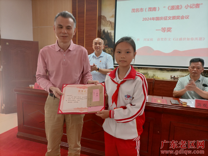 图为茂名市老促会副会长兼秘书长刘付德金给获征文一等奖的小记者刘家欣颁奖并合影.jpg